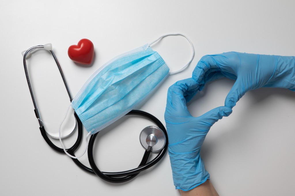 Стетоскоп, медицинская маска и руки в перчатках в форме сердца